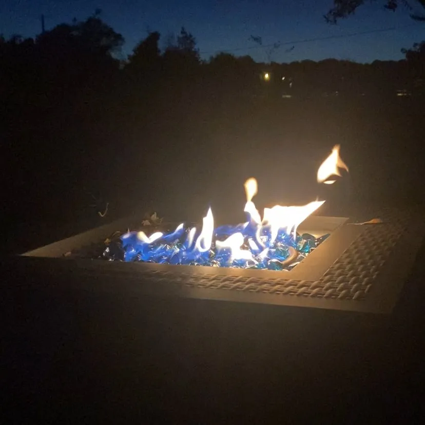 A fire pit glowing with blue glass at night.