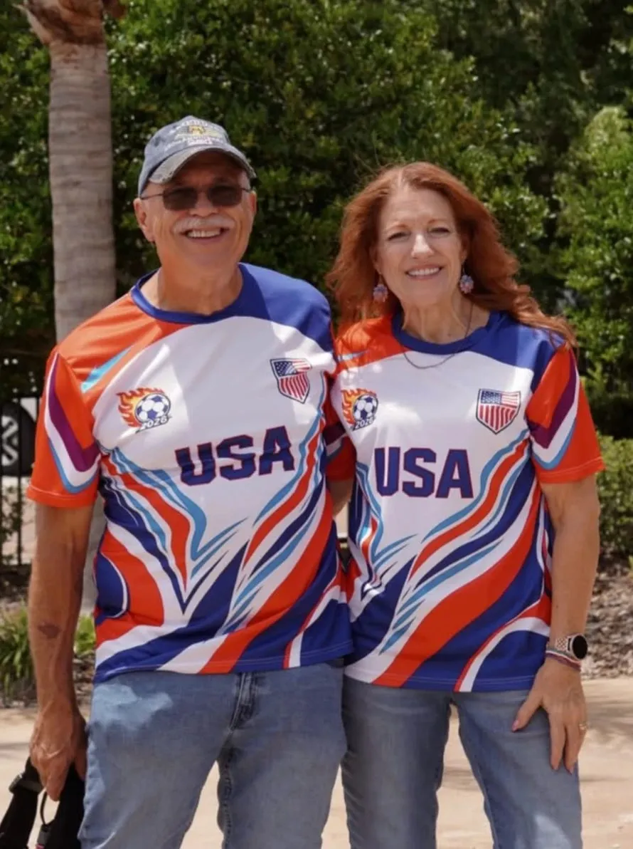 Paul and Loring Hammond in matching USA jerseys, arm in arm under the palms.