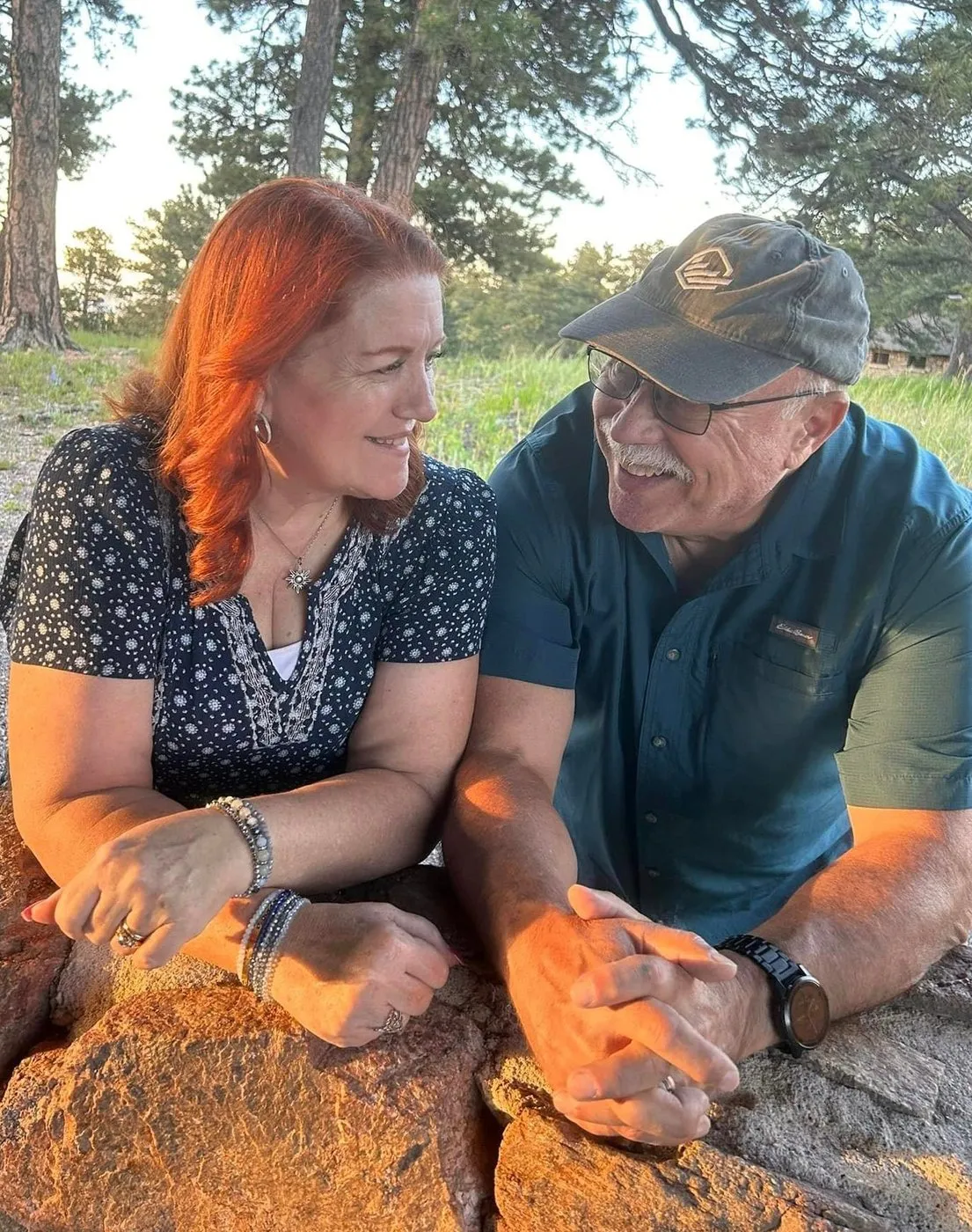 Paul and Loring leaning on a rock, laughing together at golden hour.