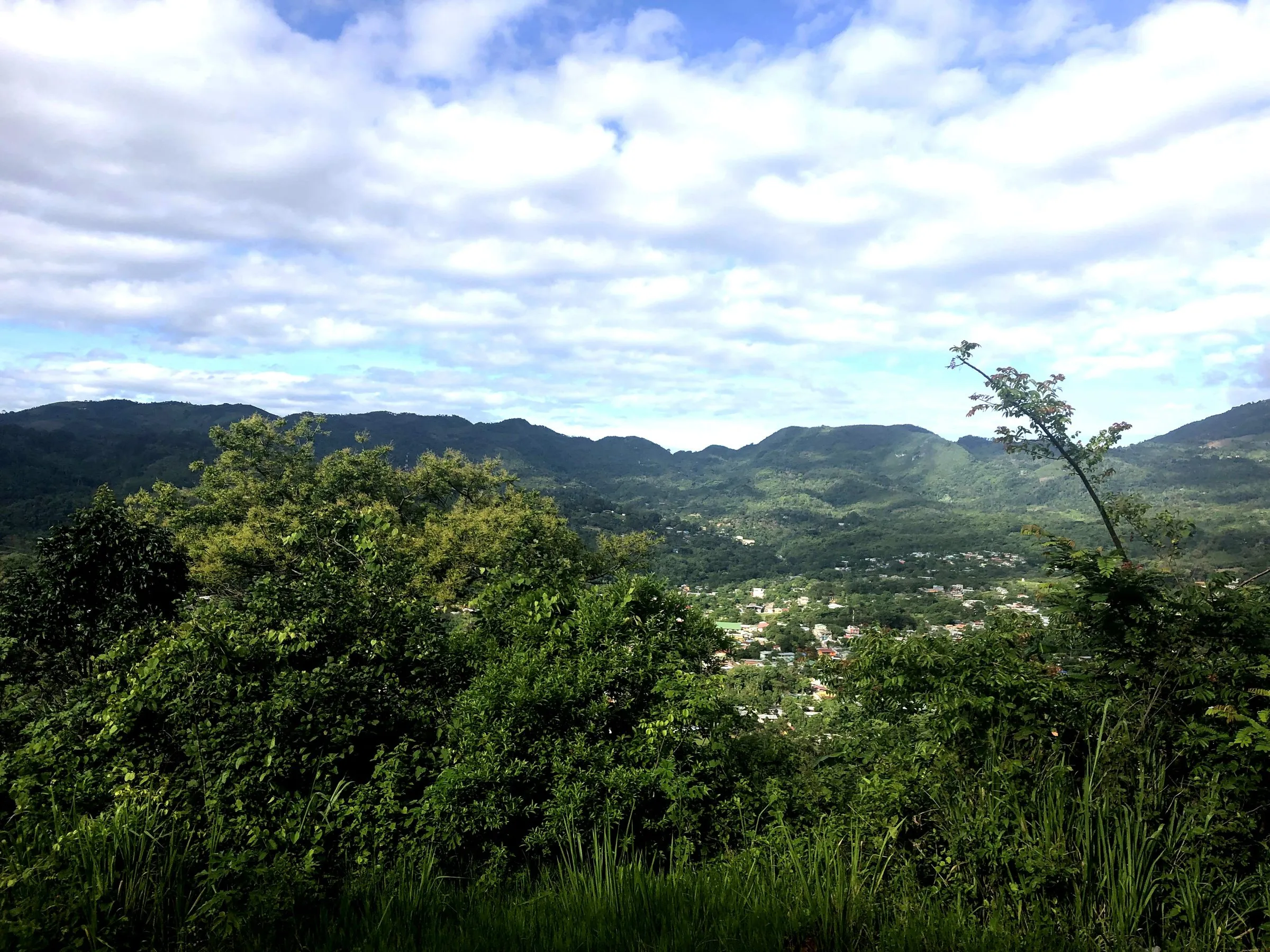 Green hills and a valley town under a wide blue sky in Honduras.
